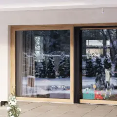 Duże okno HST z drewnianą ramą, przez które widać zimowy ogród i zabawki.