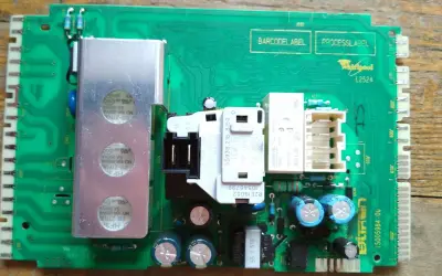 Płyta sterująca pralki Whirlpool, potencjalnie z błędem F08. Widoczne elementy to przekaźniki, kondensatory i radiator.