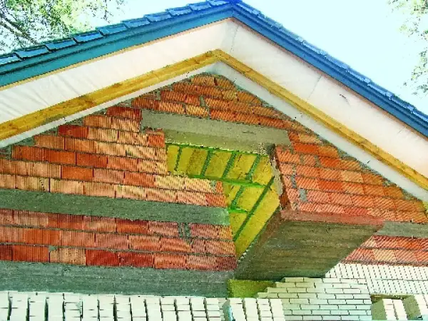 Budowa ściany szczytowej z cegły, widoczna izolacja i elementy konstrukcji dachu.