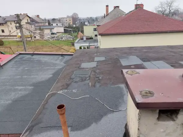 Dach płaski z papą, przygotowany do ocieplenia nakrokwiowego. Widoczny komin i rynna.